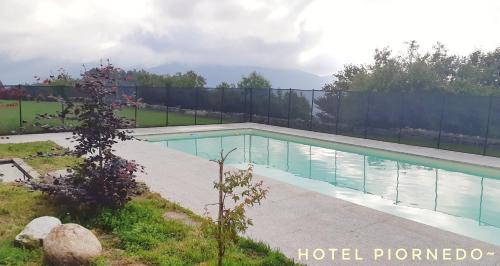 ein Pool in einem Garten mit einem Zaun in der Unterkunft HOTEL PIORNEDO in Lugo