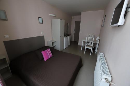 Hôtel du Roussillon في باريس: غرفة نوم صغيرة مع سرير أسود مع وسادة وردية