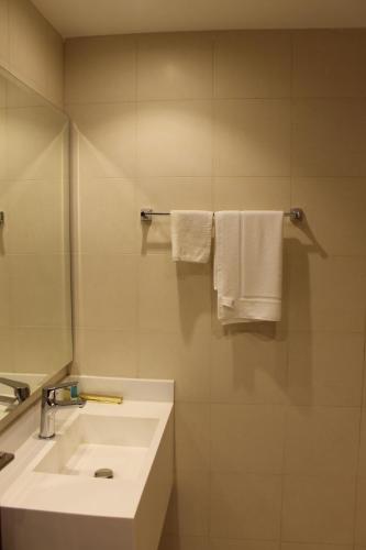 a bathroom with a sink and a mirror and towels at High Village Hotel in Al Namas