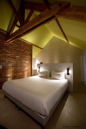 Cette chambre comprend un grand lit blanc et un mur en briques. dans l'établissement L'authentik petit hôtel LE REFUGE DE MAMIE YO, à Auzay