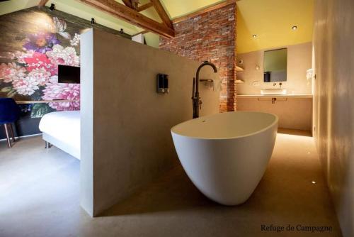 uma casa de banho com uma banheira grande e um quarto em L'authentik petit hôtel Le Refuge de Mamie Yo 