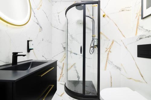 a glass shower in a bathroom with a black sink at Vola Palace in Warsaw