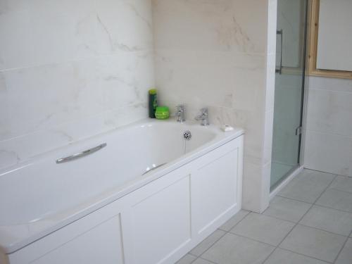 a white bathroom with a sink and a shower at The Coach House in Shepreth