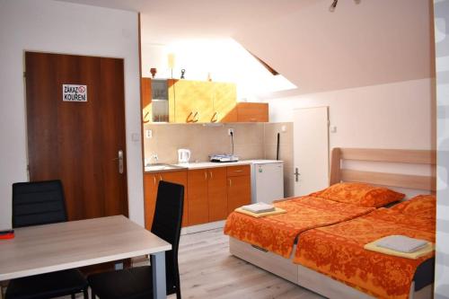 een slaapkamer met een bed en een tafel en een keuken bij Penzion Era in Zlín