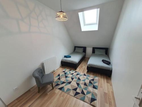 a attic room with a bed and a chair at Appartement 4 personnes proche gare et hôpital in Saint-Amand-Montrond