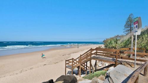 a beach with a person walking on the sand at 1 - 5a Coochin Street, Dicky Beach - 200m To Beach in Caloundra