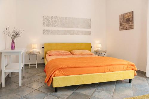 a bedroom with a bed with an orange blanket at Dolce Vita in CastellʼAlfero