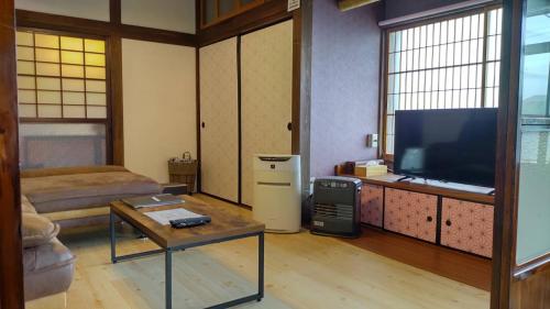 een woonkamer met een flatscreen-tv en een tafel bij ドッグラン併設 しまなみ御殿 in Imabari