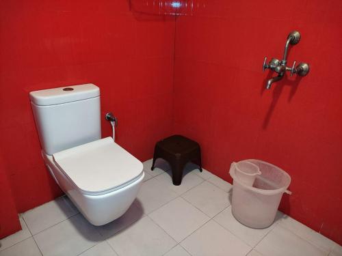 ein rotes Bad mit einem WC und einem Mülleimer in der Unterkunft Offbeat CCU Bunkers in Kalkutta