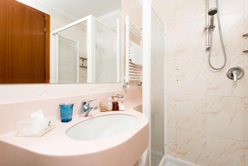 a white bathroom with a sink and a shower at Hotel Berna in Milan