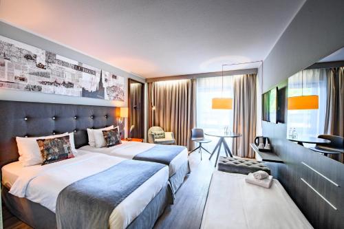 a hotel room with two beds and a desk at Holiday Inn Lübeck by IHG in Lübeck