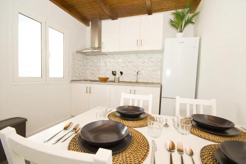 a white kitchen with a table with black dishes on it at Los Alonsos - Open Mall in Arrecife