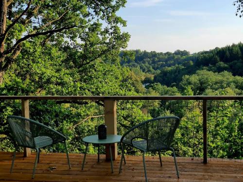 two chairs and a table on a deck with trees at Glamping Žvaigždžių slėnyje 