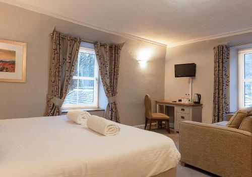 a bedroom with a bed and a couch and a window at Loch Leven Hotel & Distillery in Glencoe