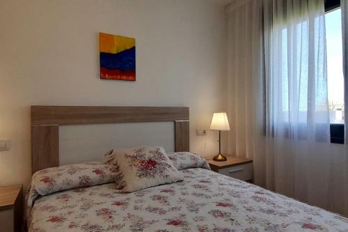 een slaapkamer met een bed met een bloemenbed en een raam bij APARTAMENTO PLAYA CATEDRALES in Barreiros
