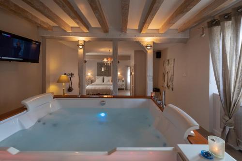 a large bath tub in a room with a bedroom at CHARME AU FIL DE L'EAU in Vendières