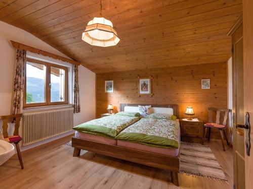 1 dormitorio con 1 cama y pared de madera en Wolkenmooshof en Sankt Johann in Tirol