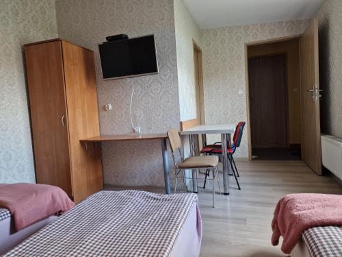 a room with a desk and a table with a tv on the wall at Noclegi Ali in Wałbrzych