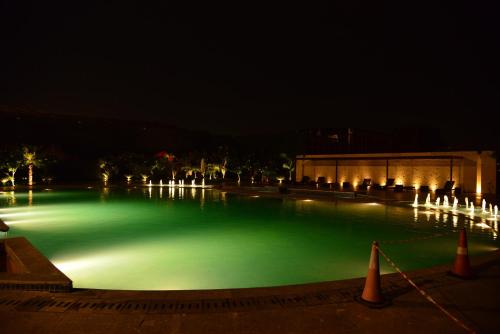 a large pool of green water at night at The Umrao in New Delhi