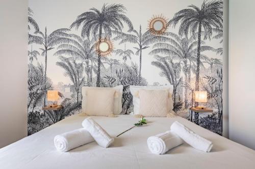 - une chambre avec un grand lit et du papier peint de palmiers dans l'établissement Bali Chic, à La Hourcade