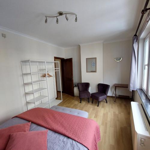 a bedroom with a bed and two chairs in it at Le Berceau des Croisades in Bouillon