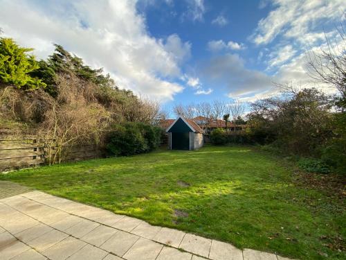 a yard with a small shed in the distance at Schoolstraat 4 in Callantsoog