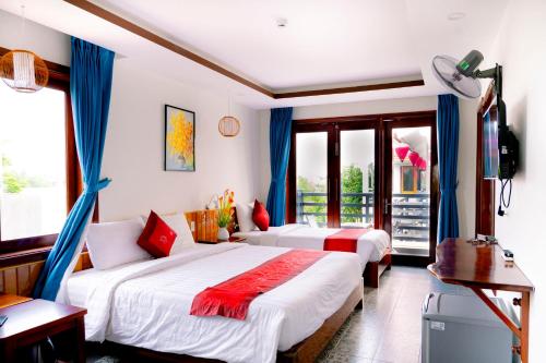 a bedroom with two beds with blue drapes at Villa Loan A HOI AN in Hoi An