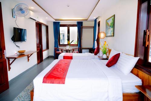a hotel room with two beds and a television at Villa Loan A HOI AN in Hoi An