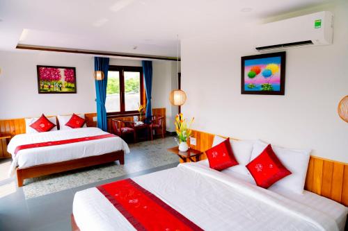 a hotel room with two beds with red pillows at Villa Loan A HOI AN in Hoi An