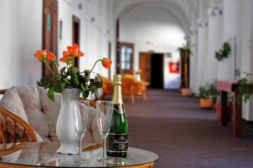 a bottle of champagne and glasses on a table with flowers at Zamek Cerveny Hradek in Jirkov