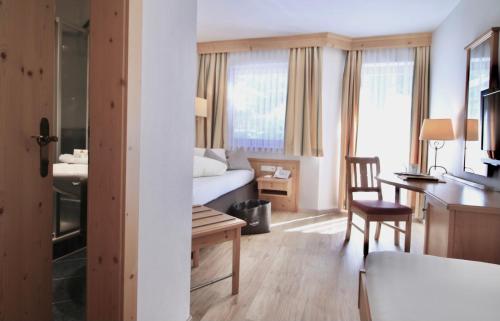 ein Hotelzimmer mit einem Bett, einem Schreibtisch und einem Tisch in der Unterkunft Stacklerhof in Neustift im Stubaital