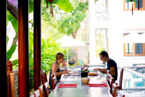 two people sitting at a table in a restaurant at Villa Loan A HOI AN in Hoi An