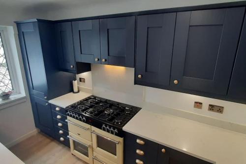 a kitchen with blue cabinets and a stove top oven at GOLF OPEN HOYLAKE Bungalow In West Kirby in West Kirby