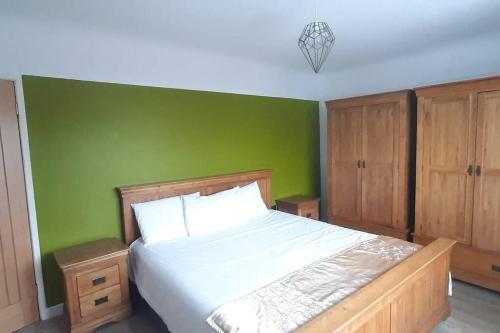 um quarto com uma cama com uma parede verde em GOLF OPEN HOYLAKE Bungalow In West Kirby em West Kirby