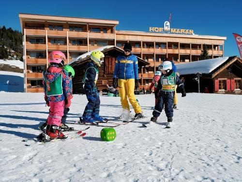 a group of children on skis in the snow in front of a hotel at Golf- & Sporthotel Hof Maran in Arosa