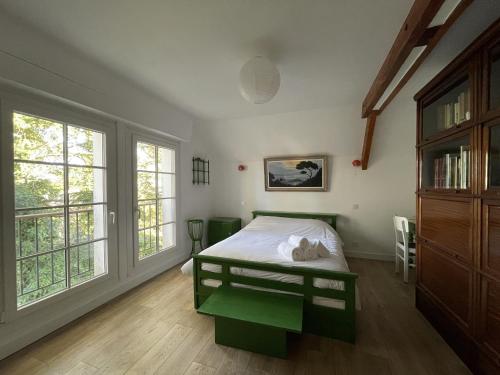 een slaapkamer met een groen bed en ramen bij Vancances relaxantes sur la Presqu ile de Rhuys in Le Tour-du-Parc