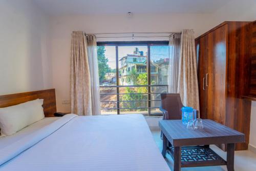 1 dormitorio con cama, mesa y ventana en Dhimahi Residency, en Mahabaleshwar
