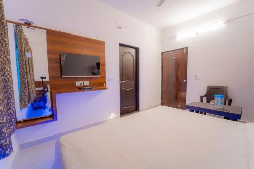 Habitación con cama y TV en la pared. en Dhimahi Residency, en Mahabaleshwar