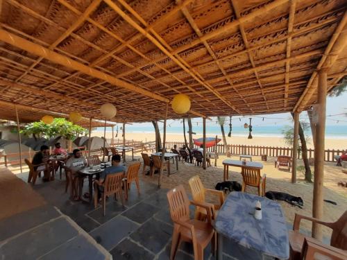 a restaurant on the beach with people sitting at tables at Trippr Gokarna - Beach Hostel in Gokarna