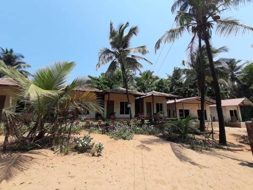 ゴカルナにあるTrippr Gokarna - Beach Hostelのヤシの木が植えられた浜辺の家