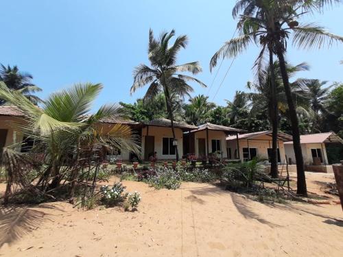 a house on the beach with palm trees at Trippr Gokarna - Beach Hostel in Gokarna