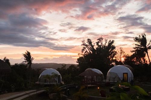 a sunset with three domes in a yard with trees at La Joya Farm Resort & Spa in Aloguinsan