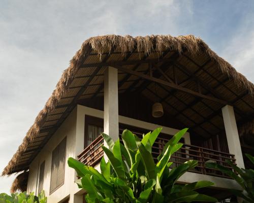 a building with a thatched roof and a plant at La Joya Farm Resort & Spa in Aloguinsan