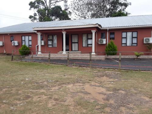 czerwony dom z płotem przed nim w obiekcie Manguzi Central Lodge w mieście Manguzi
