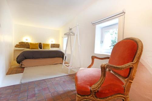 um quarto com uma cama, uma cadeira e uma janela em La petite Maison de Gordes 2 nuits minimum em Gordes