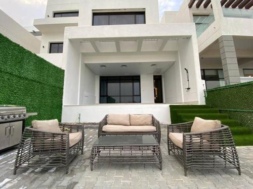 a patio with three chairs and a couch in front of a building at Chalet 2200 in Al Khīrān