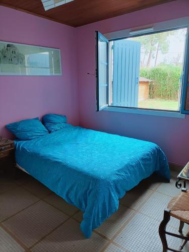 une chambre avec un lit avec une couette bleue et une fenêtre dans l'établissement Itzala, à Andernos-les-Bains