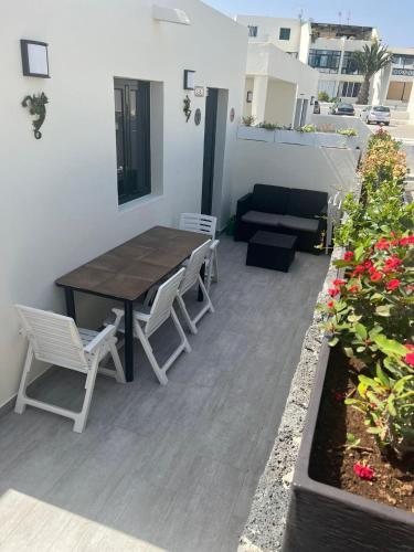 a patio with a wooden table and chairs and a couch at luxury casa playa roca bord de mer in Costa Teguise