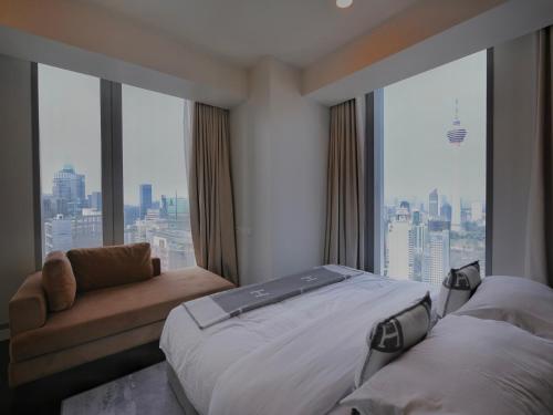 Habitación de hotel con cama, sofá y ventanas en Tropicana The Residences - KLCC VIEW Luxury Apartment Collections, en Kuala Lumpur