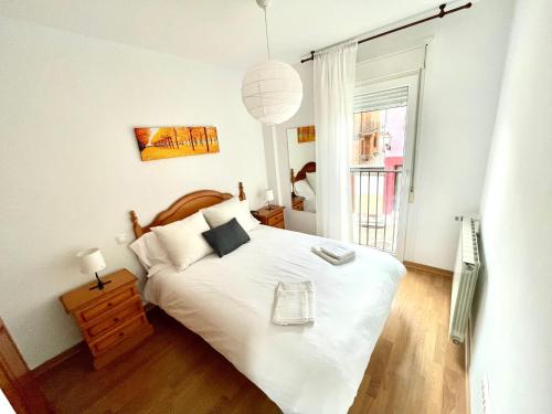 Un dormitorio con una gran cama blanca y una ventana en Casa Pyrene - Acogedor apartamento familiar, en Sabiñánigo
